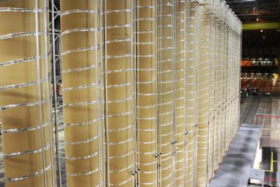Tall, narrow tan-colored cylinders with coiled metal wire around them form a HALEU enrichment cascade.