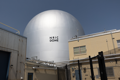 The NRIC DOME facility at INL, a tall, silver dome-shaped building against a blue sky.