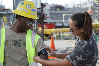 A woman placing a safety armband on a man in safety gear
