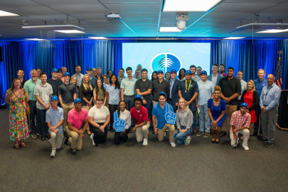 A large group of interns posing for a photo in front of a blue wall