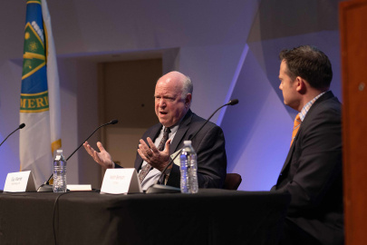 Two individuals sitting at a table speaking into microphones.