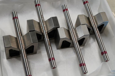 Four silver metallic fuel rod samples on display