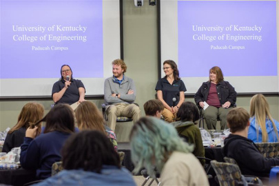 Four individuals sitting on stage participating in a panel in front of an audience