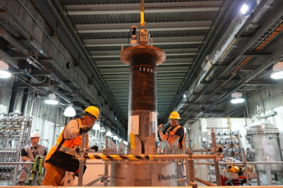 Employees in protective gear standing beside a large flow filter inside a facility building
