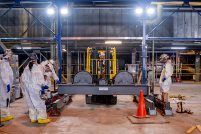 Employees in protective gear use a roller stand at the Paducah Site