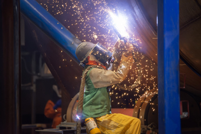 An employee in protective gear welding a converter