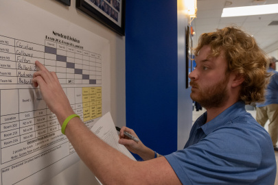 An employee in a blue shirt points at something written on a poster on the wall