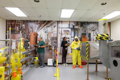 Employees in protective gear working on safety mockups