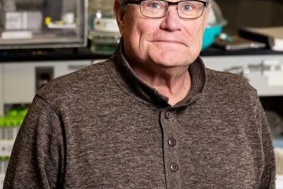 A headshot of an older gentleman wearing glasses inside a laboratory