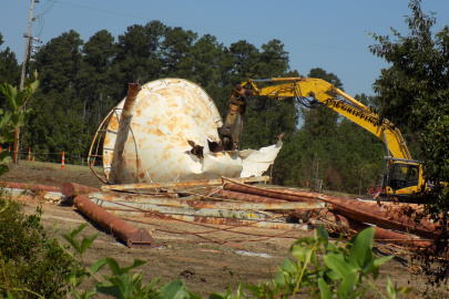 A large white water tower being demolished by construction vehicles at the Savannah River Site