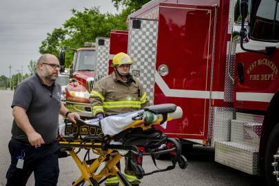 Two emergency responders pushing a gurney during a training drill, they are walking beside a firetruck