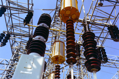 Electrical substation with high-voltage transformers, insulators, and switchgear connected by overhead transmission equipment.