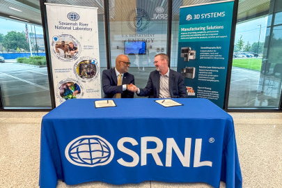 A pair of professionals sitting at a table with a blue tablecloth, they face each other and shake hands