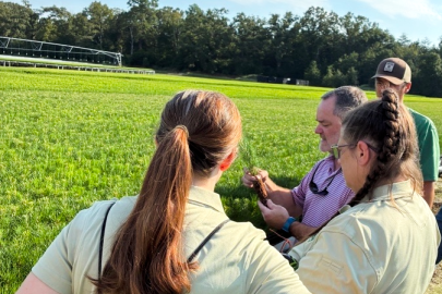 Four employees outside at the Savannah River Site looking at a screen that one of them is holding