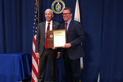 Two professionals holding an award posing for a photo together