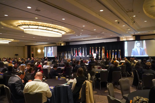 Opening session at the 2022 Tribal Clean Energy Summit in a large ballroom with tribal flags on the stage.