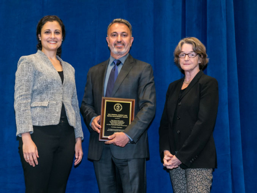 Individuals posing with an award plaque.