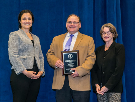 Individuals posing with an award plaque.