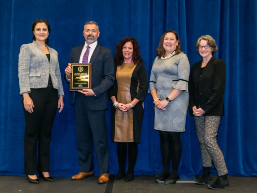 Individuals posing with an award plaque.