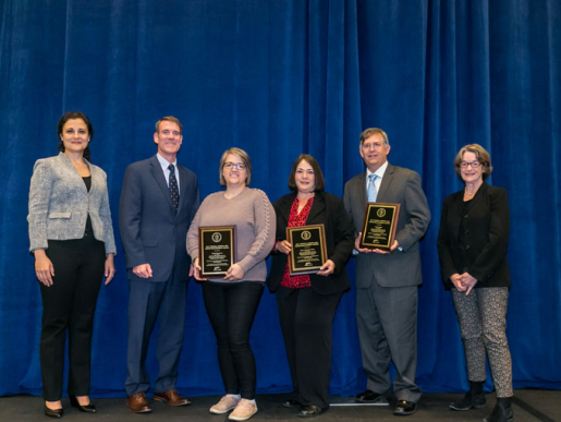 Individuals posing with an award plaque.