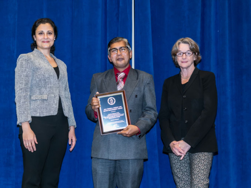 Individuals posing with an award plaque.