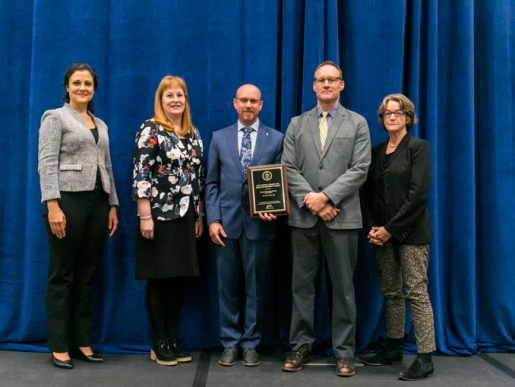 Individuals posing with an award plaque.