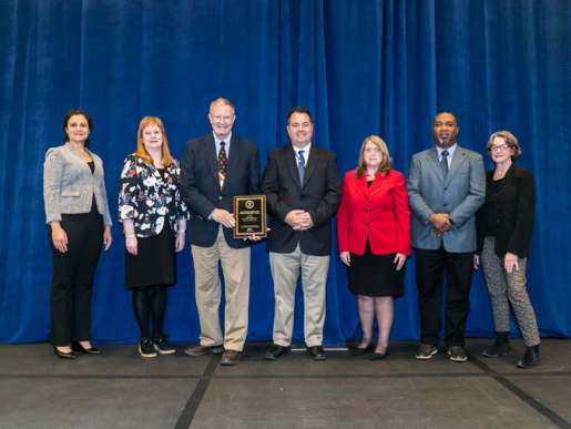 Individuals posing with an award plaque.