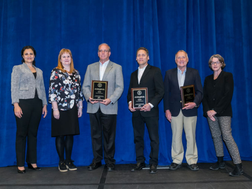 Individuals posing with an award plaque.