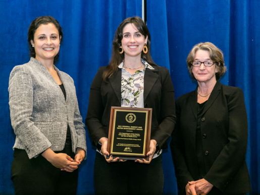 Individuals posing with an award plaque.