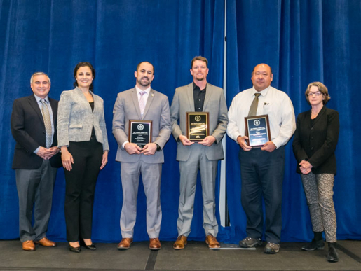 Individuals posing with an award plaque.