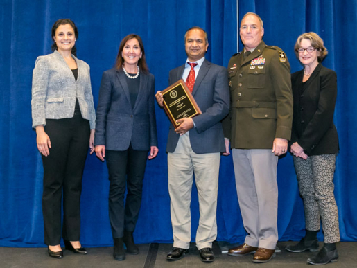 Individuals posing with an award plaque.