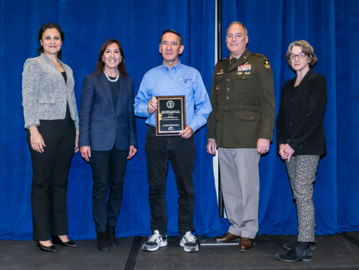 Individuals posing with an award plaque.