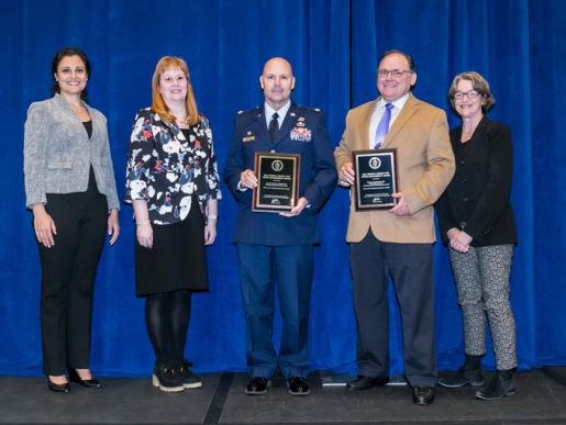 Individuals posing with an award plaque.