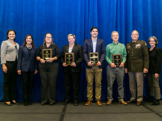 Individuals posing with an award plaque.