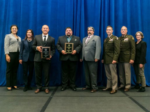 Individuals posing with an award plaque.