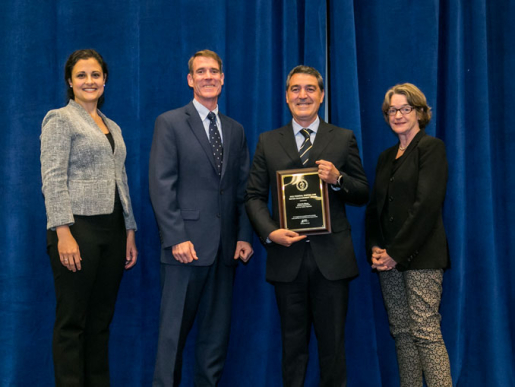 Individuals posing with an award plaque.