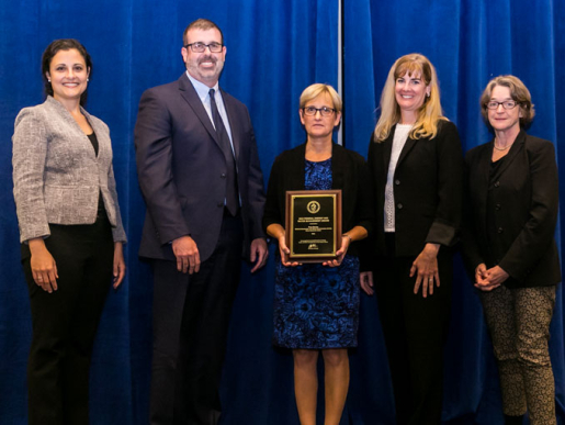 Individuals posing with an award plaque.