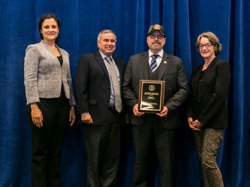 Individuals posing with an award plaque.