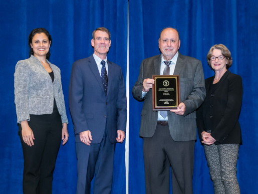 Individuals posing with an award plaque.