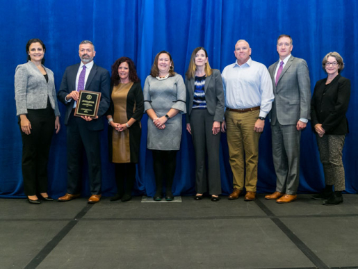 Individuals posing with an award plaque.