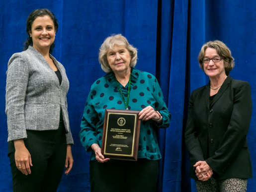 Individuals posing with an award plaque.