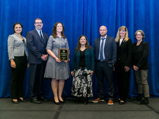 Individuals posing with an award plaque.