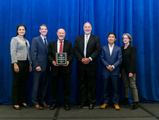 Individuals posing with an award plaque.