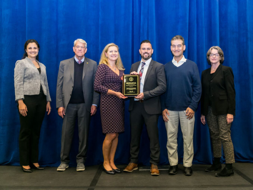 Individuals posing with an award plaque.