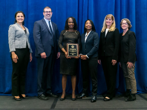 Individuals posing with an award plaque.