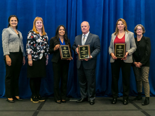 Individuals posing with an award plaque.