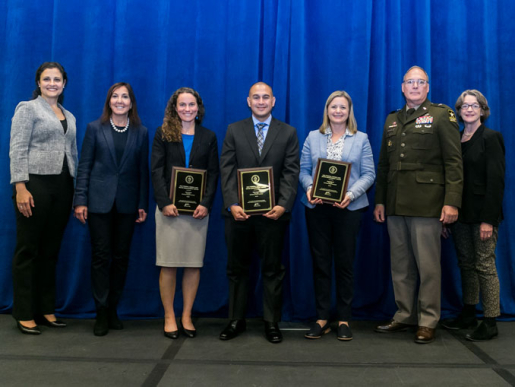 Individuals posing with an award plaque.