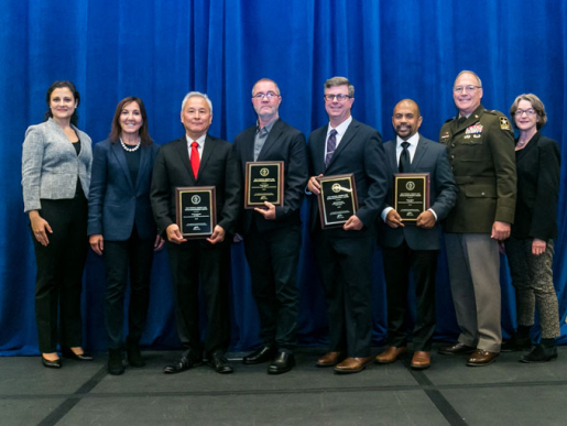 Individuals posing with an award plaque.