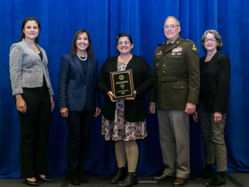 Individuals posing with an award plaque.