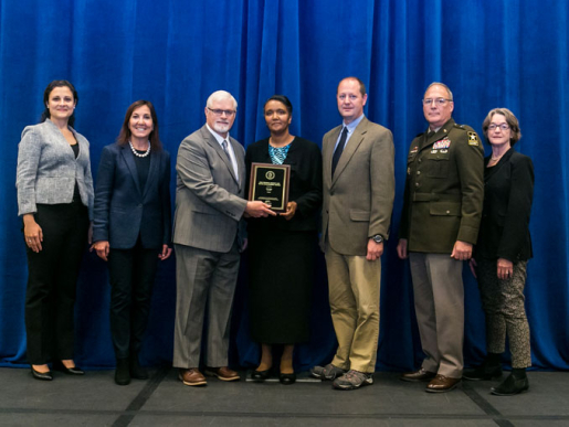 Individuals posing with an award plaque.